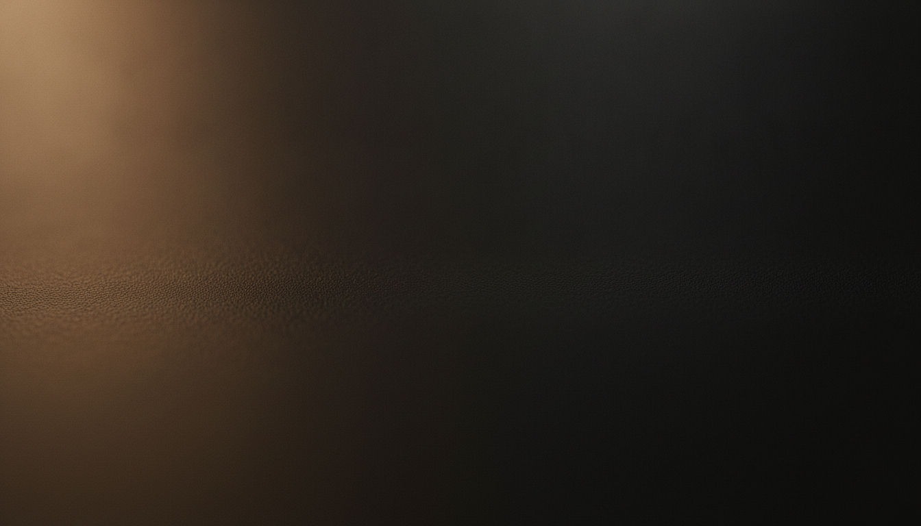 Dark anodized metal with a quiet warm amber glow pooling in the lower left